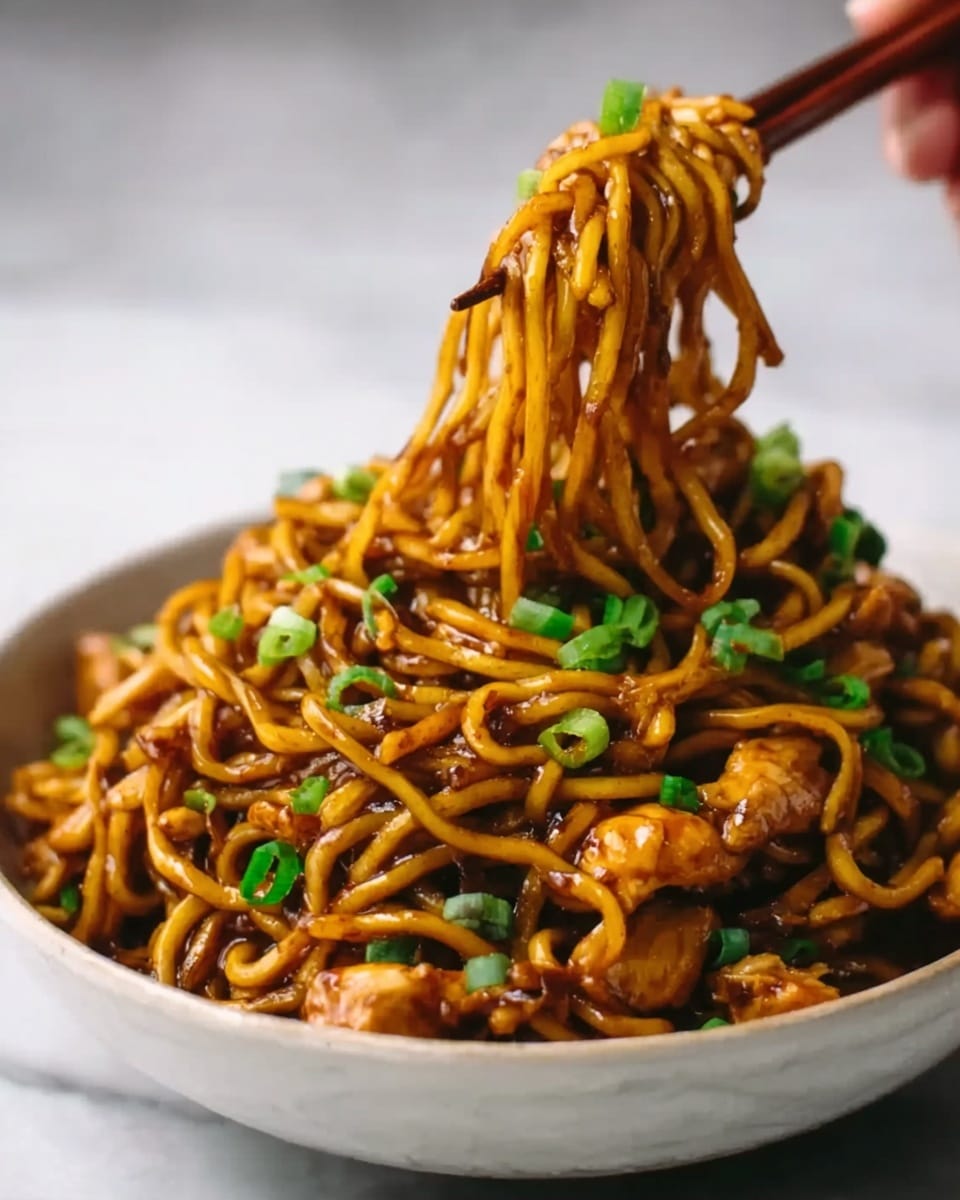 A close-up view of a white bowl filled with dark brown noodles coated in a glossy sauce. The noodles are thick and slightly twisted, and pieces of cooked chicken are mixed throughout. The dish is topped with chopped green onions that add a burst of color. A woman's hand is lifting a bundle of noodles on chopsticks above the bowl, showing the texture and thickness of the noodles. The bowl sits on a white marbled surface. photo taken with an iphone --ar 4:5 --v 7
