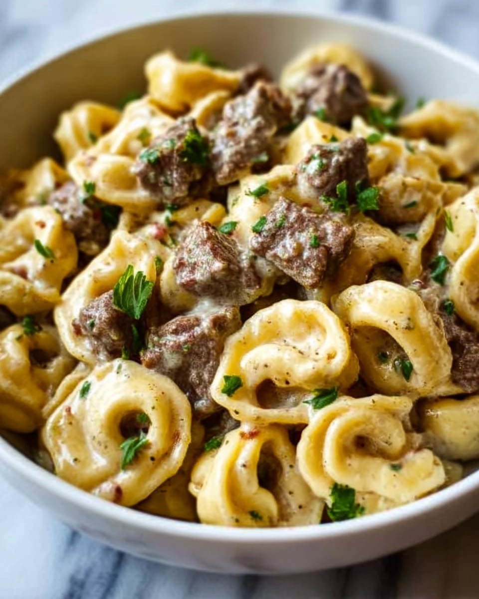 A close-up of a white bowl filled with creamy pasta tortellini mixed with tender pieces of browned beef. The tortellini are yellow with a smooth texture, swirled with a light, creamy sauce that coats each piece. The beef has a rich brown color with a slightly crispy look. Small green parsley leaves are scattered on top, adding a fresh touch. The background has a white marbled texture. Photo taken with an iphone --ar 4:5 --v 7