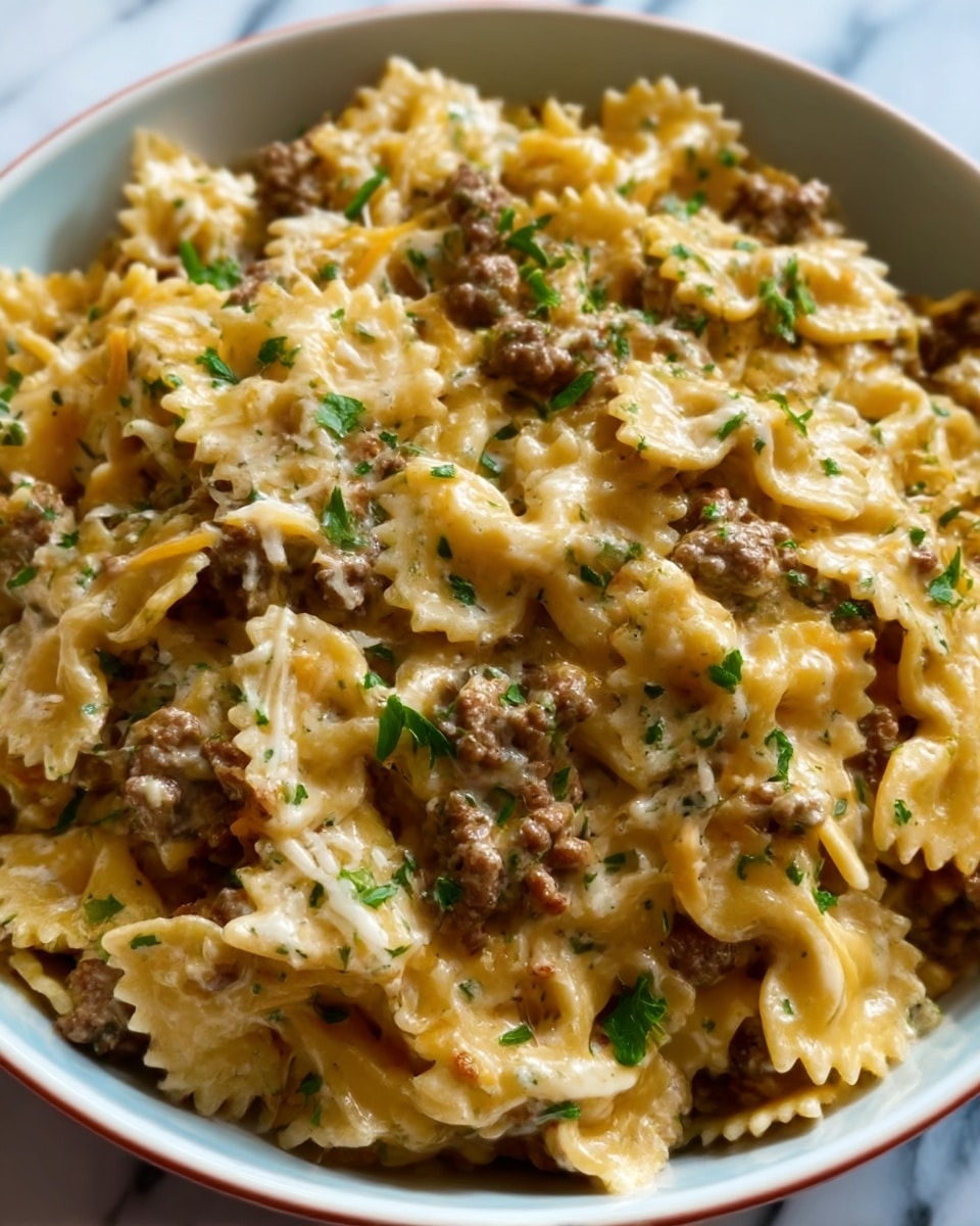 The image shows a close-up of a bowl filled with bowtie pasta mixed with browned ground beef. The pasta is creamy and looks soft, coated in a light cheese sauce. There are small bits of melted cheese spread throughout, and fresh green parsley pieces are sprinkled on top for color. The bowl is white, placed on a white marbled surface. Photo taken with an iphone --ar 4:5 --v 7